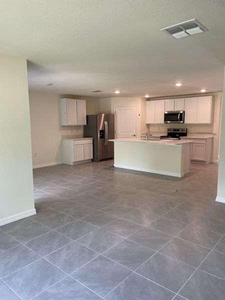 A sleek kitchen with white cabinets, stainless steel appliances, and gray tile flooring, bathed in natural light. A sleek kitchen with white cabinets, stainless steel appliances, and gray tile flooring, bathed in natural light.