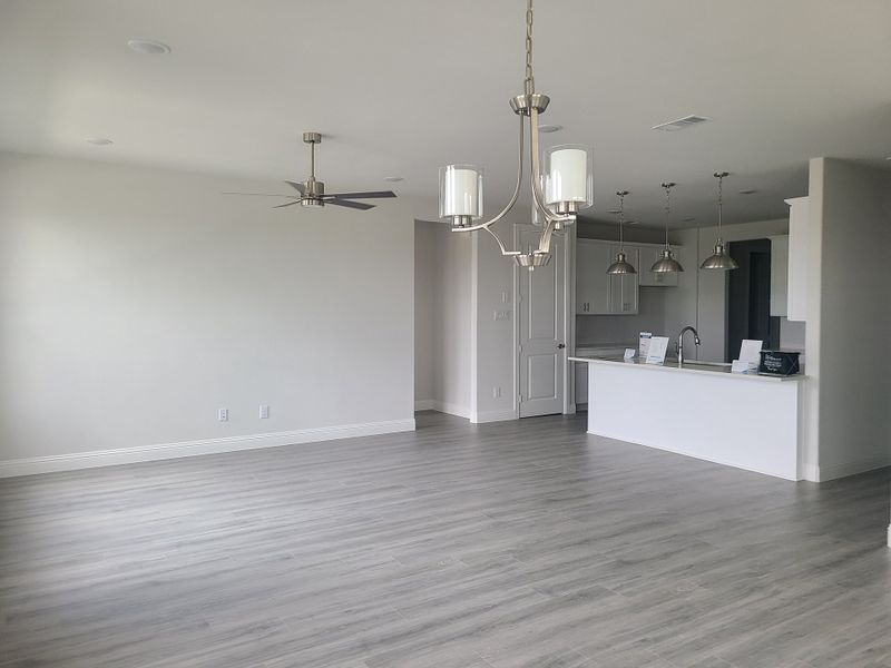 A spacious open-plan interior featuring light wood floors, modern fixtures, and a sleek white kitchen with pendant lighting. A spacious open-plan interior featuring light wood floors, modern fixtures, and a sleek white kitchen with pendant lighting.
