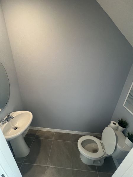 A cozy bathroom with a pedestal sink, tiled floor, and minimalist decor.