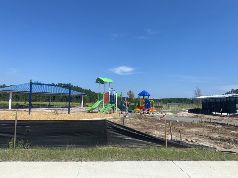 A vibrant playground under blue skies in Atlantis Pointe by Dream Finders Homes (Middleburg, FL), featuring colorful slides and structures.
