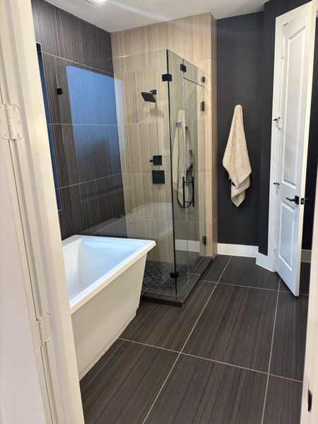 A modern bathroom featuring a sleek glass shower, freestanding tub, and elegant tiled walls. A modern bathroom featuring a sleek glass shower, freestanding tub, and elegant tiled walls.