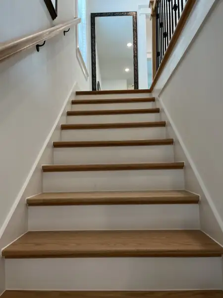 A contemporary staircase with wooden steps, elegant railings, and a large framed mirror enhancing the modern interior.