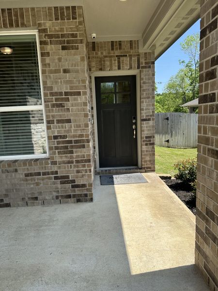 A charming brick entryway with a black front door and a window, set in Pine Lake Cove - Premier Series by Meritage Homes (Conroe, TX).