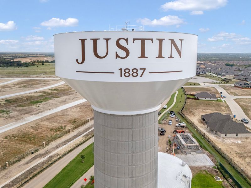 Aerial view of Justin Texas water tower marked 1887 with new residential neighborhood and open land nearby Aerial view of Justin Texas water tower marked 1887 with new residential neighborhood and open land nearby