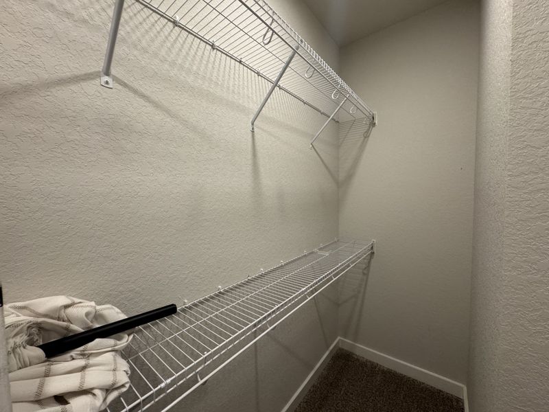 A compact closet with white wire shelving and beige walls, offering practical storage space. A compact closet with white wire shelving and beige walls, offering practical storage space.