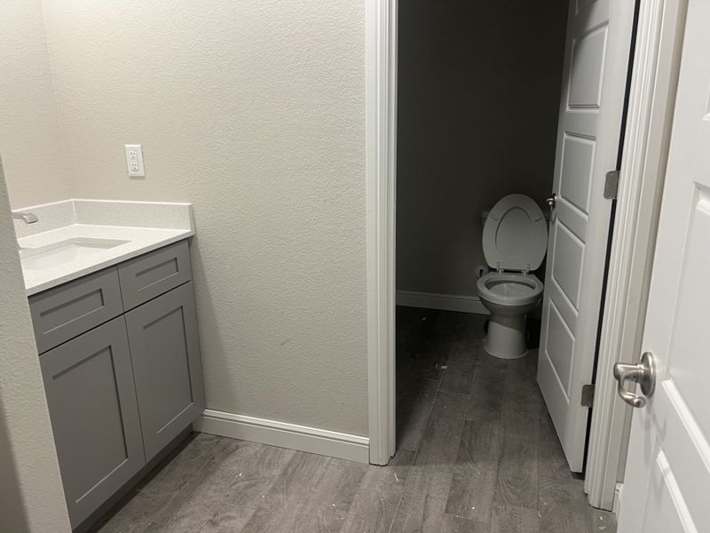 A modern bathroom with a sleek gray vanity, white countertop, and private toilet area. A modern bathroom with a sleek gray vanity, white countertop, and private toilet area.