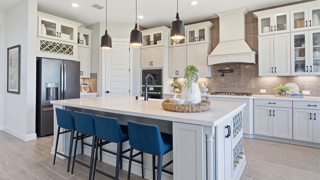 Elegant kitchen in Mostyn Manor Reserve featuring a grand island, chic pendant lighting, and custom cabinetry.