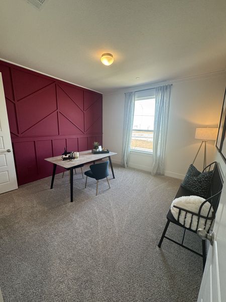 A chic office with a striking burgundy accent wall, modern desk, and cozy seating.