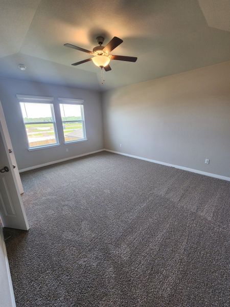 A bright bedroom with soft carpeting, high ceilings, and large windows, offering a peaceful and comfortable atmosphere.
