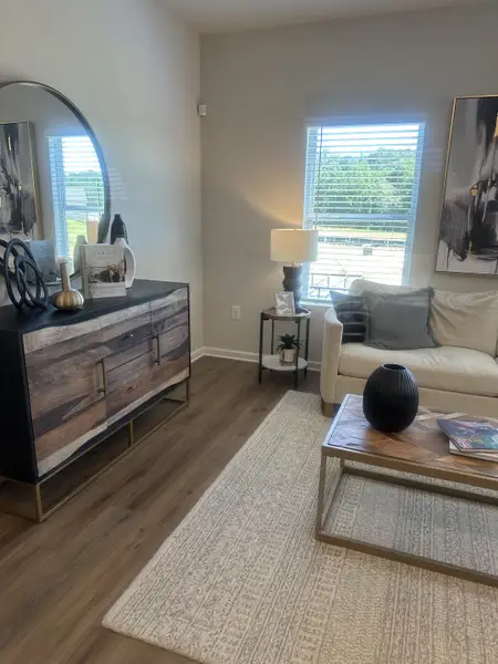 A cozy living room with modern decor, featuring a wooden sideboard, light sofa, and elegant window view. A cozy living room with modern decor, featuring a wooden sideboard, light sofa, and elegant window view.