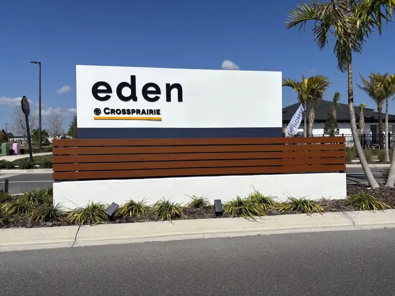 The welcoming entrance of Eden at Crossprairie, featuring modern signage and lush landscaping by M/I Homes (St. Cloud, FL).