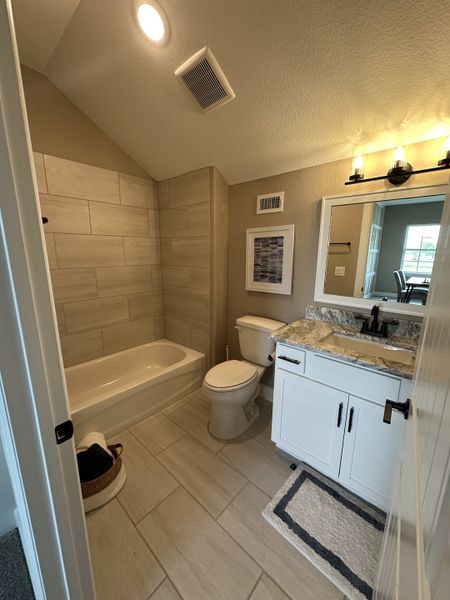 A cozy bathroom with beige tile, a white vanity, granite countertop, and stylish lighting. A cozy bathroom with beige tile, a white vanity, granite countertop, and stylish lighting.