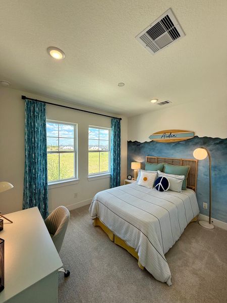 A cozy bedroom with a surf-themed decor, featuring a striped bed, vibrant drapes, and a dedicated study area. A cozy bedroom with a surf-themed decor, featuring a striped bed, vibrant drapes, and a dedicated study area.