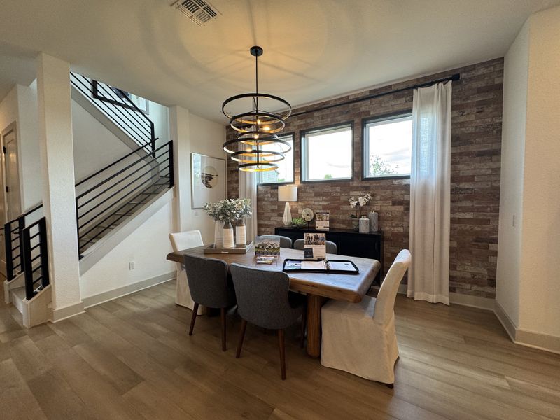 A modern dining area with a rustic brick accent wall, stylish lighting, and elegant decor.