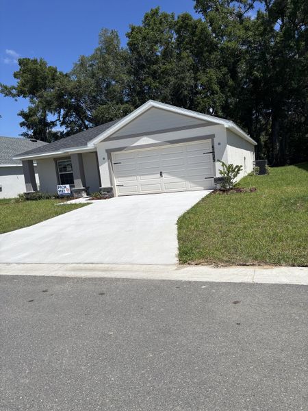 A charming white home with a lush yard in Bennah Oaks by Highland Homes of Florida, Belleview, FL.