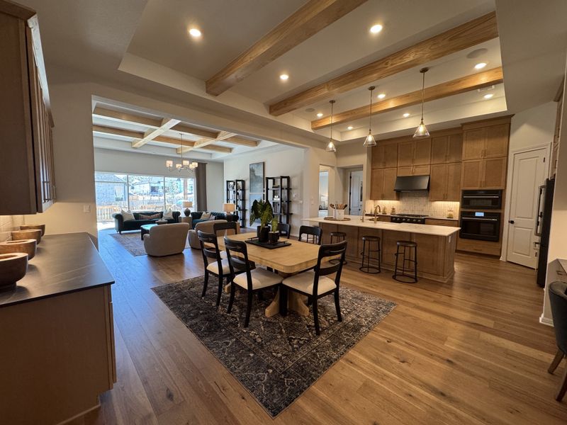 A spacious open-concept kitchen and living area with wood beams, elegant lighting, and cozy seating.