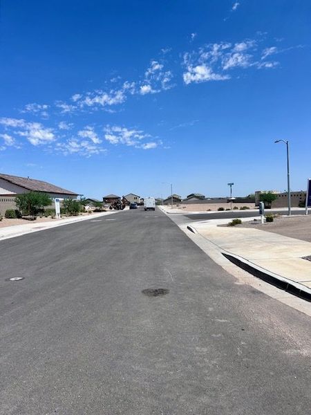 A tranquil street view in Amarillo Creek by Starlight Homes, showcasing wide roads and desert landscaping (Maricopa, AZ).