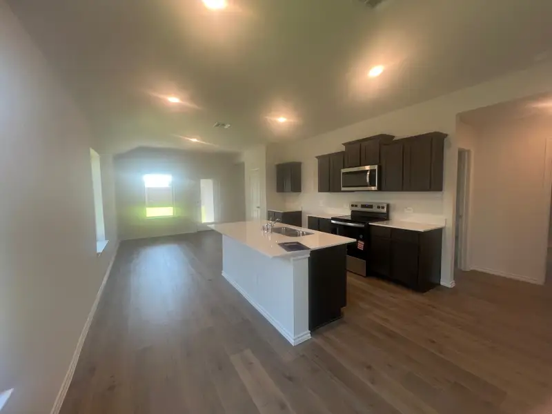 A modern kitchen with sleek dark cabinets, stainless steel appliances, and an open layout with hardwood floors. A modern kitchen with sleek dark cabinets, stainless steel appliances, and an open layout with hardwood floors.