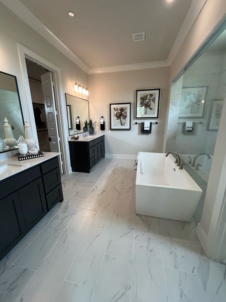 A sleek bathroom with marble-look tiles, dual vanities, modern fixtures, and wall art creates a luxurious atmosphere.