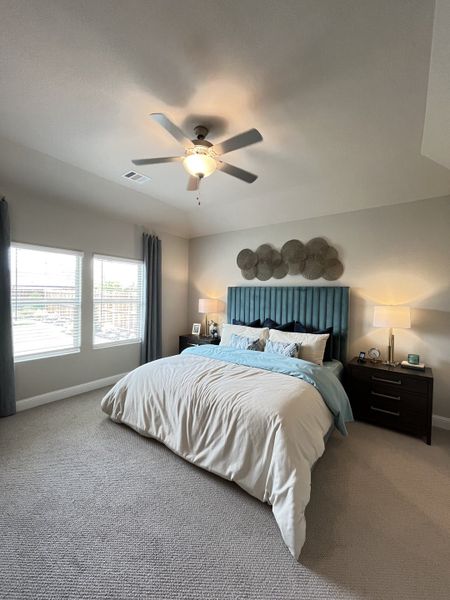 A cozy bedroom with a plush bed, teal headboard, and soft lighting. Neutral tones create a serene and inviting atmosphere.