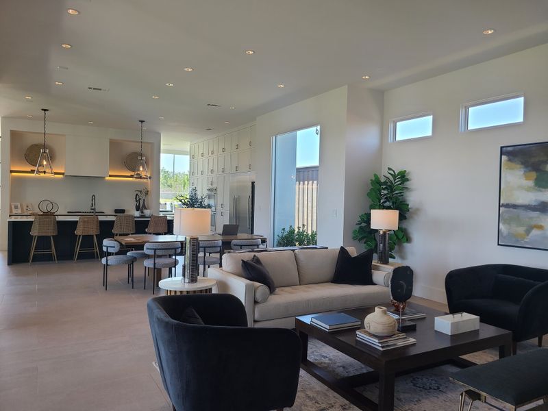 A contemporary living area with an open kitchen, featuring cozy seating, elegant lighting, and modern decor.