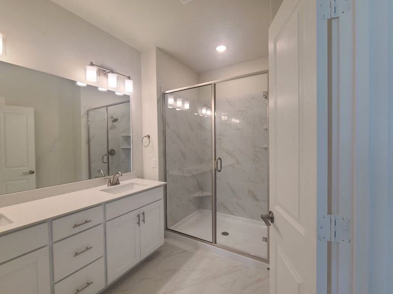 Modern bathroom featuring a sleek double vanity, spacious glass shower, and elegant lighting for a sophisticated feel.