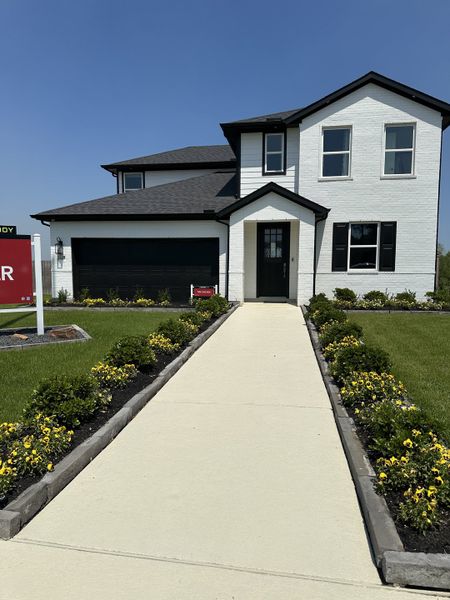 A modern white brick home with sleek black accents and lush landscaping in Montgomery Ridge: Founders Collection by Beazer Homes (Montgomery, TX).
