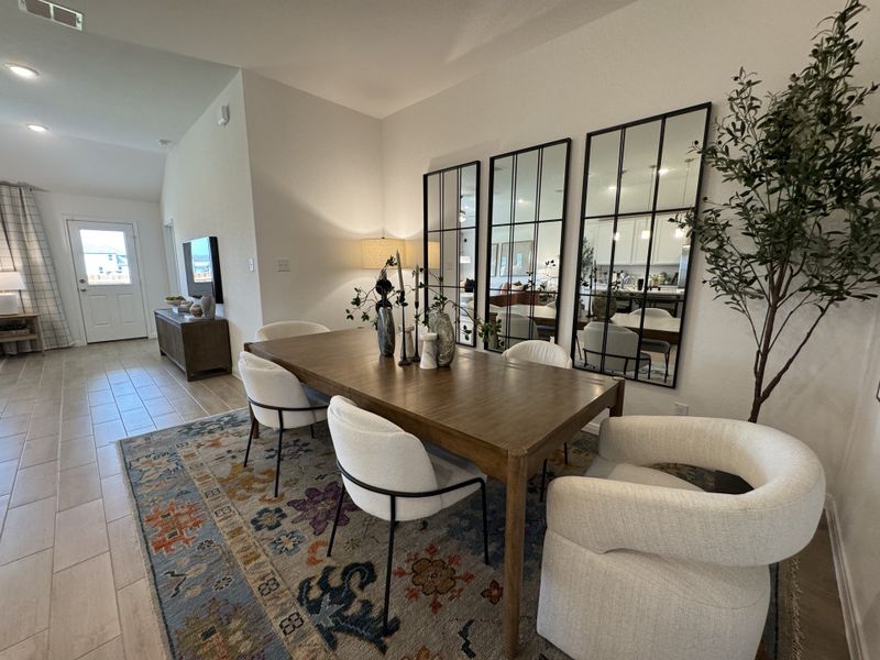 A modern dining area featuring a wooden table, stylish chairs, and full-wall mirrors, complemented by elegant decor.