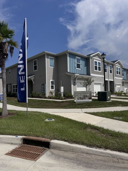 A modern gray townhouse with white trim and manicured landscaping in Longbay Townhomes by Lennar (Middleburg, FL).
