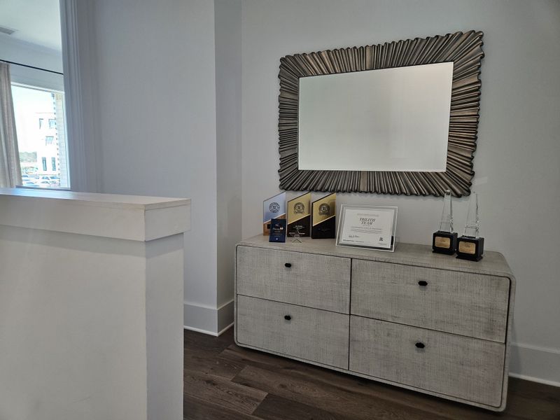 A chic interior featuring a textured dresser adorned with awards, beneath a decorative sunburst mirror.