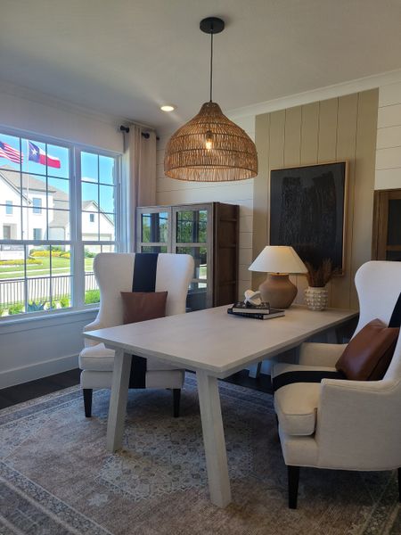 A cozy office with modern chairs, a sleek table, and a woven pendant light, featuring a large window view. A cozy office with modern chairs, a sleek table, and a woven pendant light, featuring a large window view.