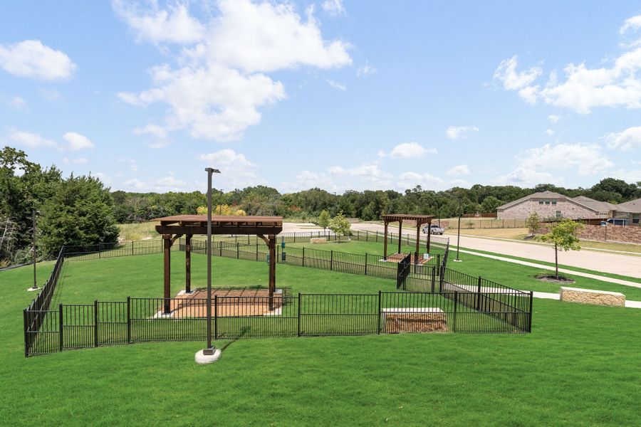 Fenced dog park with wooden pergolas, green grass, and separate small and large dog areas in a residential community