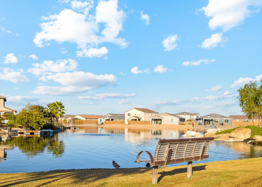 A bench next to a body of water with buildings in the background.