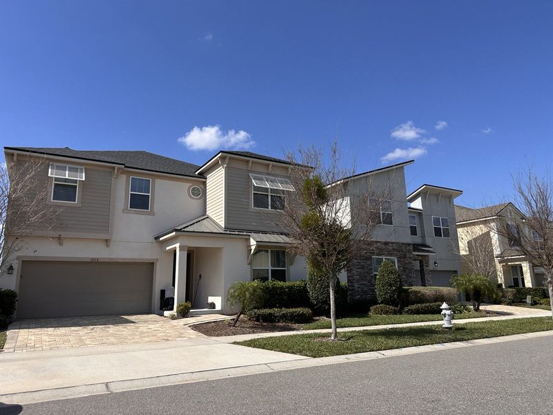 A modern two-story home with neutral tones and lush landscaping in Solara Resort by Mattamy Homes (Kissimmee, FL).