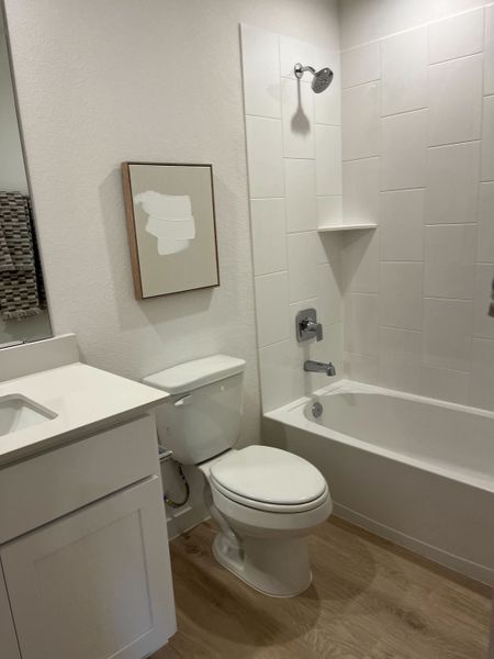 A sleek bathroom with a white vanity, modern bathtub, and stylish artwork on textured walls.