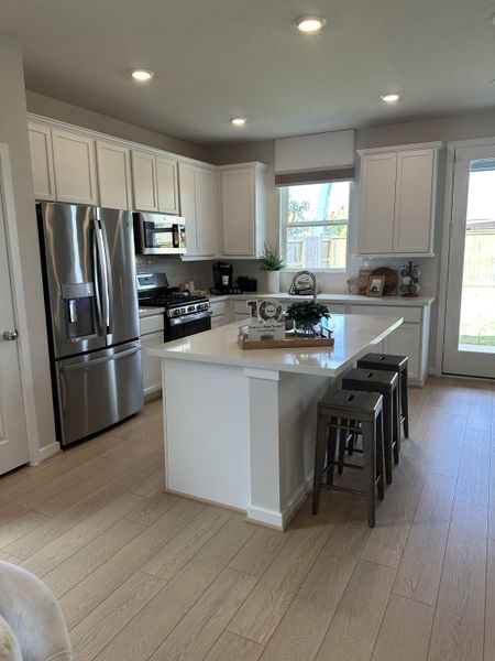 A modern kitchen with white cabinets, stainless steel appliances, and a central island with seating. A modern kitchen with white cabinets, stainless steel appliances, and a central island with seating.
