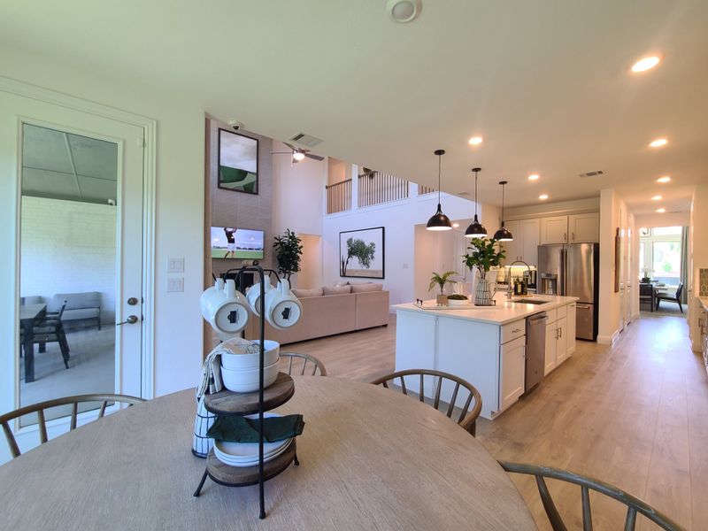 A spacious open-plan kitchen and dining area with sleek lighting, modern decor, and elegant wooden flooring.