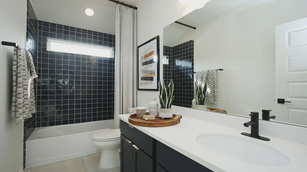 Luxurious bathroom features sleek black tiles and elegant white countertop, creating a chic in Woodlands Hills.
