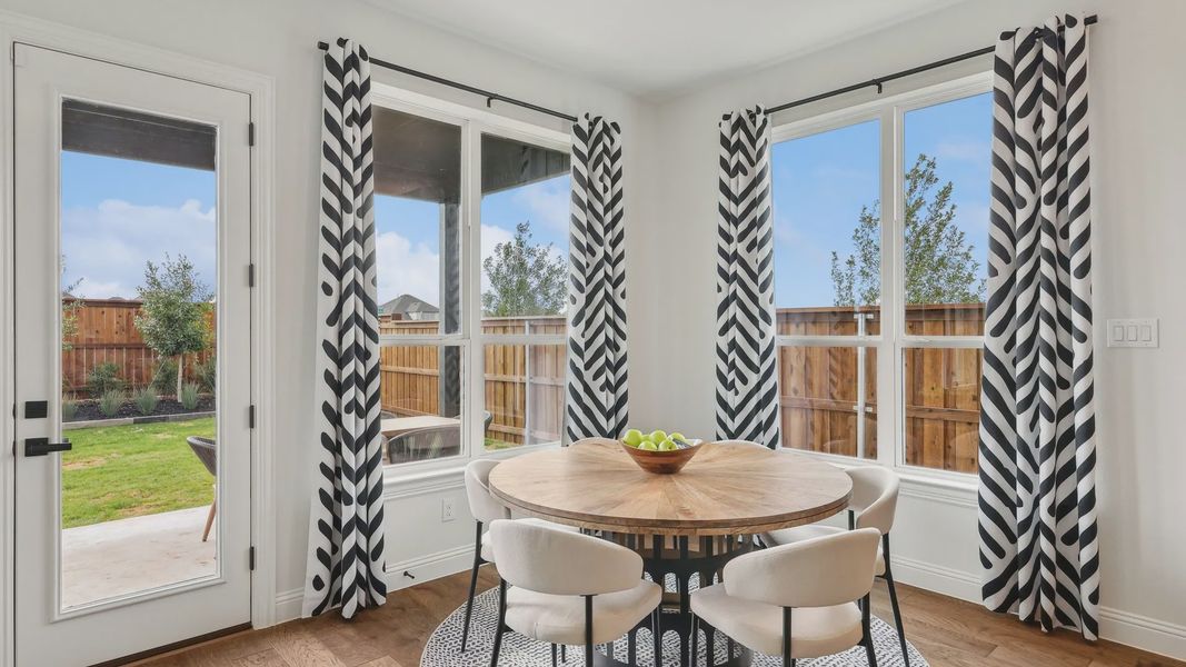 Revel in a chic dining area featuring a round wood table, striking curtains, and expansive windows in Green Meadows. Revel in a chic dining area featuring a round wood table, striking curtains, and expansive windows in Green Meadows.