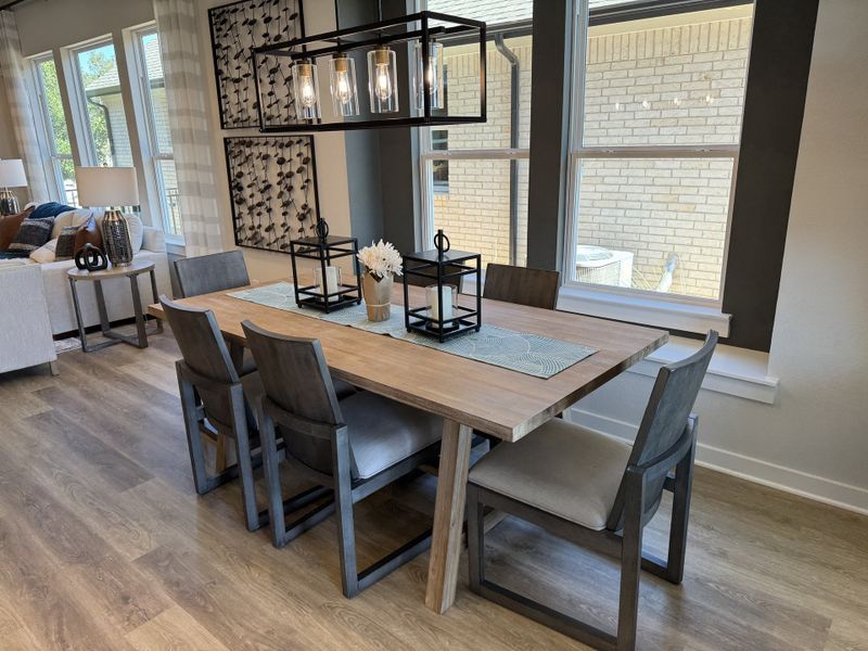 A modern dining room with a sleek wooden table, contemporary chairs, and elegant pendant lighting.