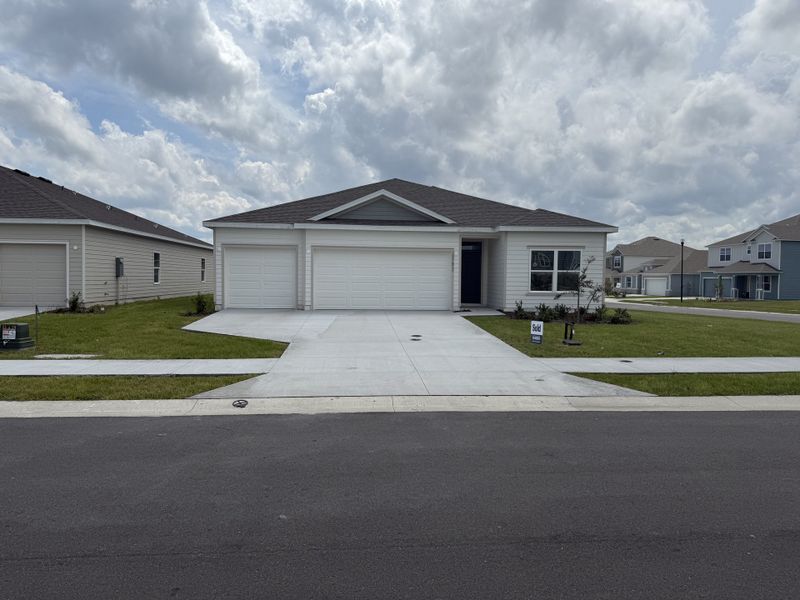 A modern single-story home with a spacious driveway in Avalon Woods by D.R. Horton, Newberry, FL.