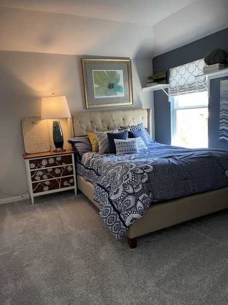 A cozy bedroom with a tufted bed, patterned bedding, chic artwork, and warm lighting creates a serene atmosphere. A cozy bedroom with a tufted bed, patterned bedding, chic artwork, and warm lighting creates a serene atmosphere.