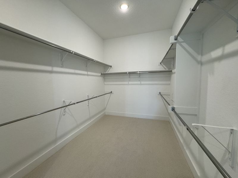 A spacious walk-in closet with ample shelving and hanging space, perfect for organized storage. A spacious walk-in closet with ample shelving and hanging space, perfect for organized storage.