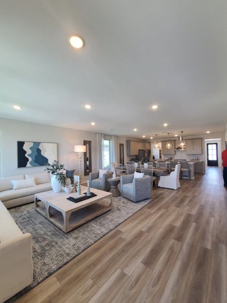 Spacious living area with modern decor, light wood floors, and ample natural light flowing from large windows.