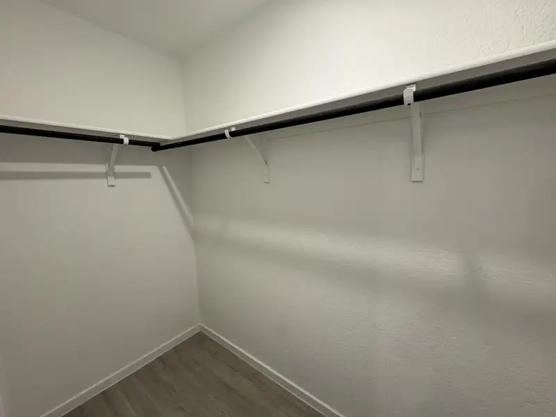 A spacious walk-in closet with sleek laminate flooring and sturdy shelves for ample storage. A spacious walk-in closet with sleek laminate flooring and sturdy shelves for ample storage.