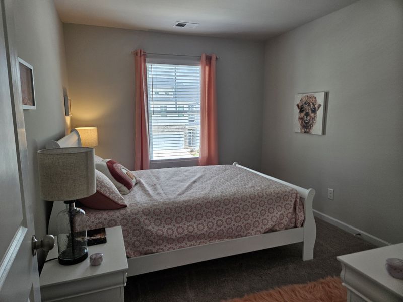 A cozy bedroom with soft lighting, pink accents, and animal artwork, perfect for relaxation and comfort.