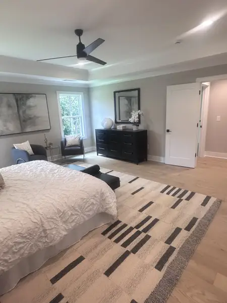 A serene bedroom with a cozy white bedspread, sleek ceiling fan, and modern decor on a patterned rug. A serene bedroom with a cozy white bedspread, sleek ceiling fan, and modern decor on a patterned rug.
