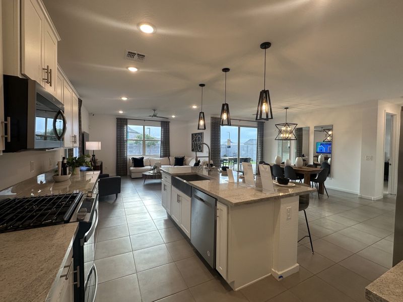 An open-concept kitchen and dining area with granite countertops, pendant lighting, and a spacious island for entertaining.