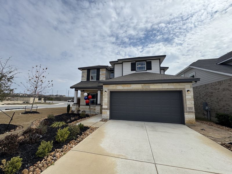 A modern two-story home with a spacious driveway and landscaped yard in Hunters Ranch by First America Homes (San Antonio, TX).