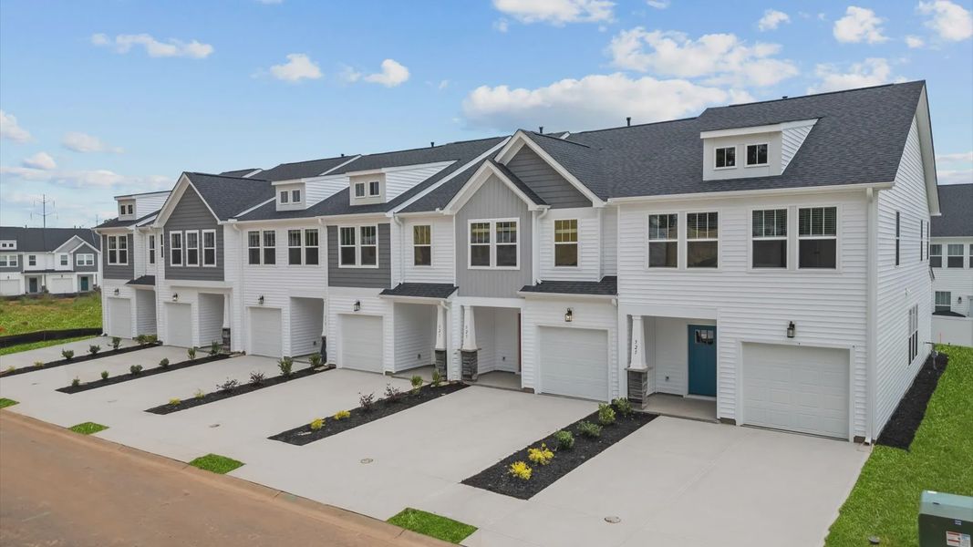 Townhome with white and grey exteriors and a two-car parking pad in Greenville, SC at Hickory Heights by DRB Homes